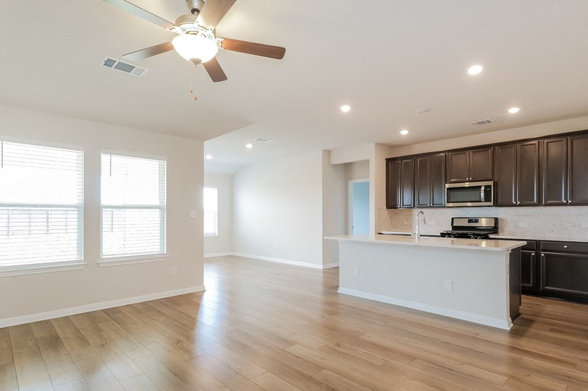 an empty living room and kitchen with a ceiling fan