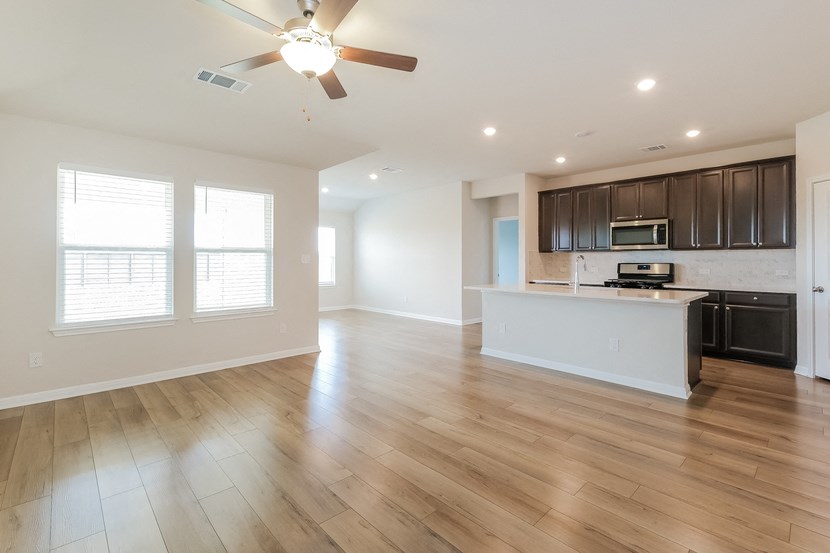 an empty living room and kitchen with a ceiling fan