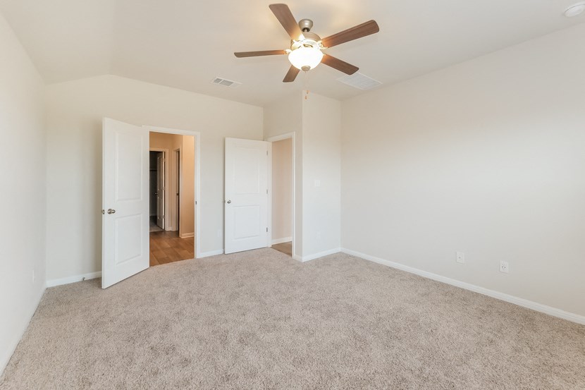 a spacious living room with carpet and a ceiling fan