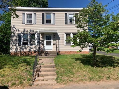 a house with stairs and a tree in front of it
