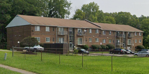 A large brick apartment building with a parking lot in front.