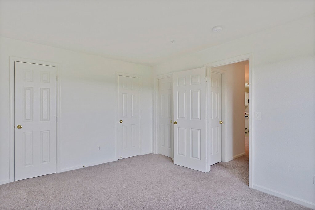 a bedroom with three doors and a carpeted floor