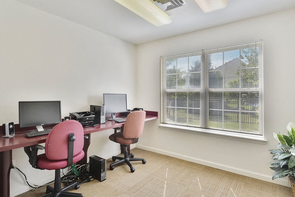 two computers sitting on a desk in a room with a window