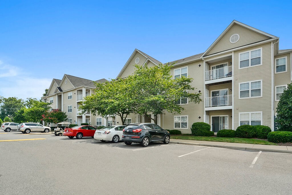 a parking lot with cars in front of an apartment building