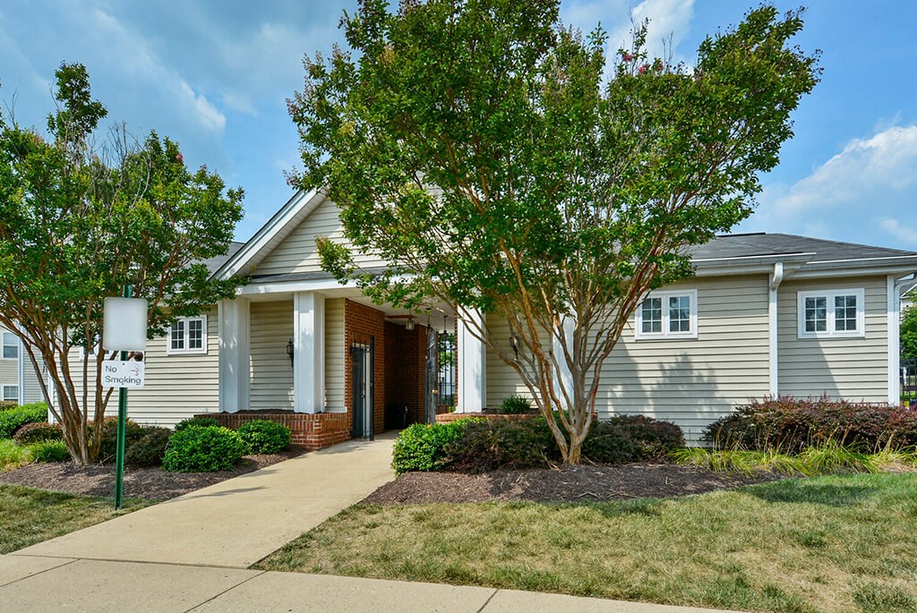 a small white house with a sidewalk in front of it