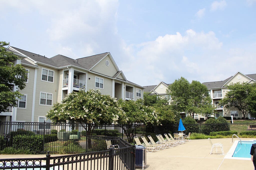 a pool with chairs in front of a row of apartments