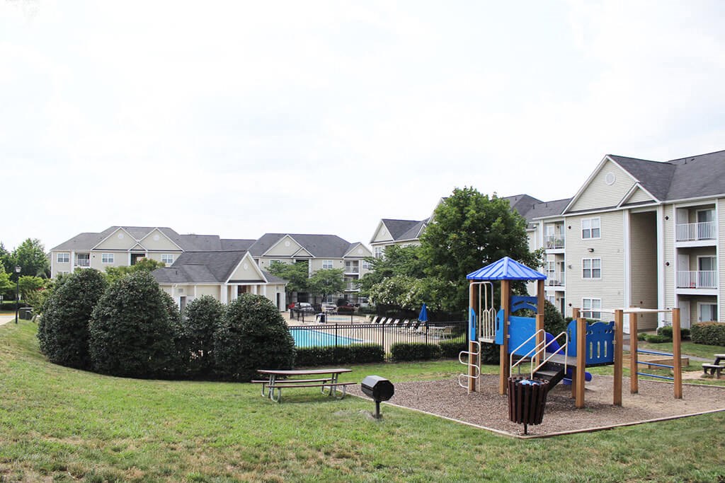 a playground in a park with houses in the background