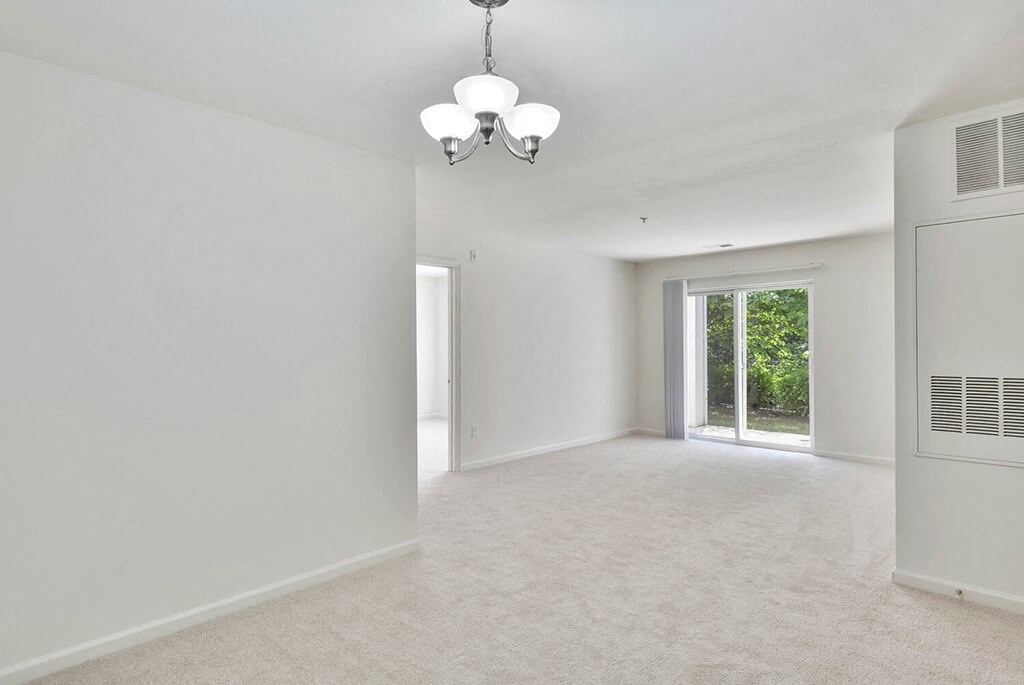 an empty living room with a window and a chandelier