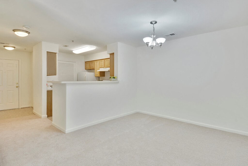an empty living room and kitchen with a white wall