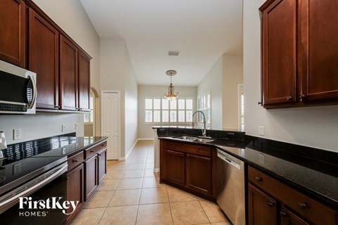 A kitchen with brown cabinets and black countertops.