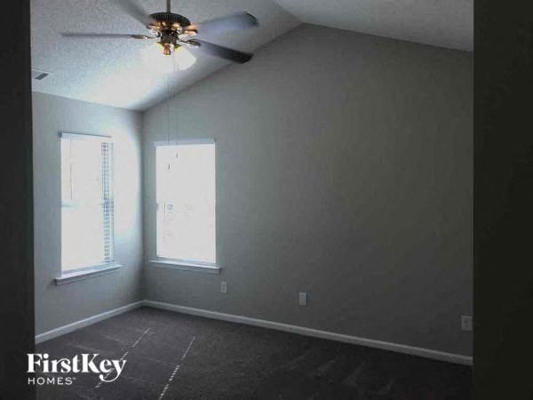 an empty room with a ceiling fan and two windows