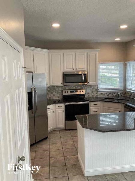 A kitchen with a refrigerator, microwave, oven, and sink.