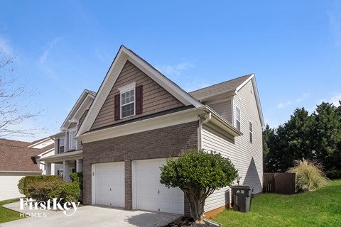 A two-story house with a garage and a tree in front.