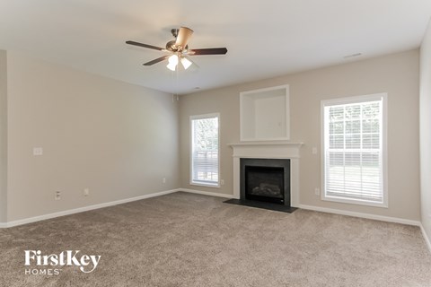 A spacious living room with a fireplace and a ceiling fan.