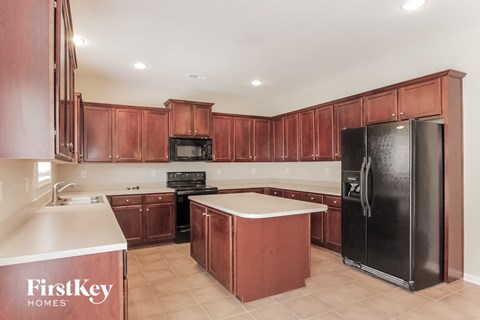 A kitchen with wooden cabinets and a black refrigerator.