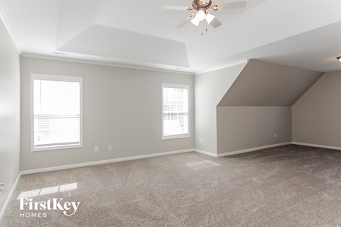A spacious room with a ceiling fan and two windows.