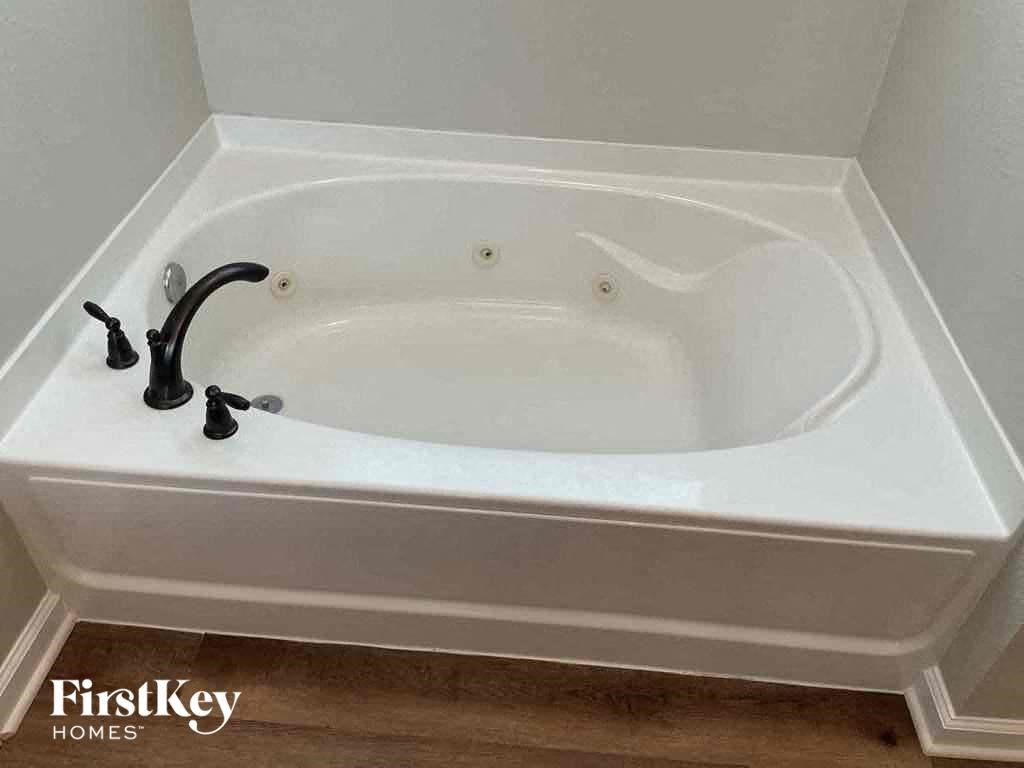a white bath tub in a bathroom with a black faucet