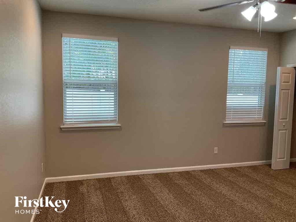 a empty living room with a carpeted floor and two windows