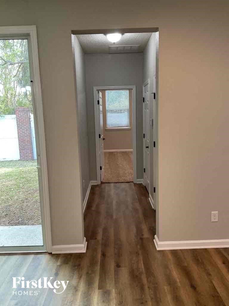 a hallway with a hard wood floor and a door into a room