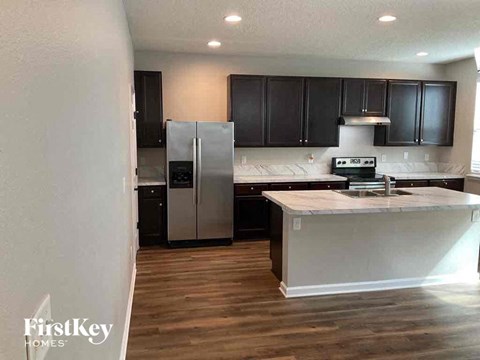 a kitchen with black cabinets and a stainless steel refrigerator