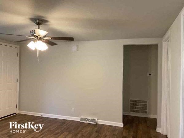 A room with a ceiling fan and a door on the right side.