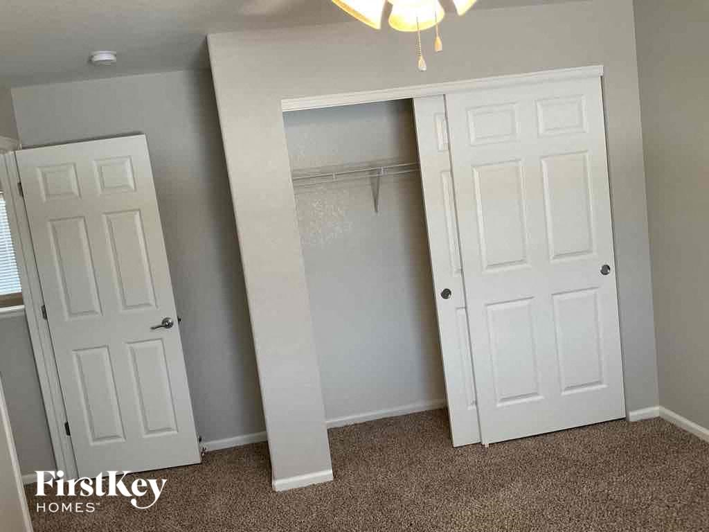an empty closet with two doors and a closet mirror in a room with gray walls