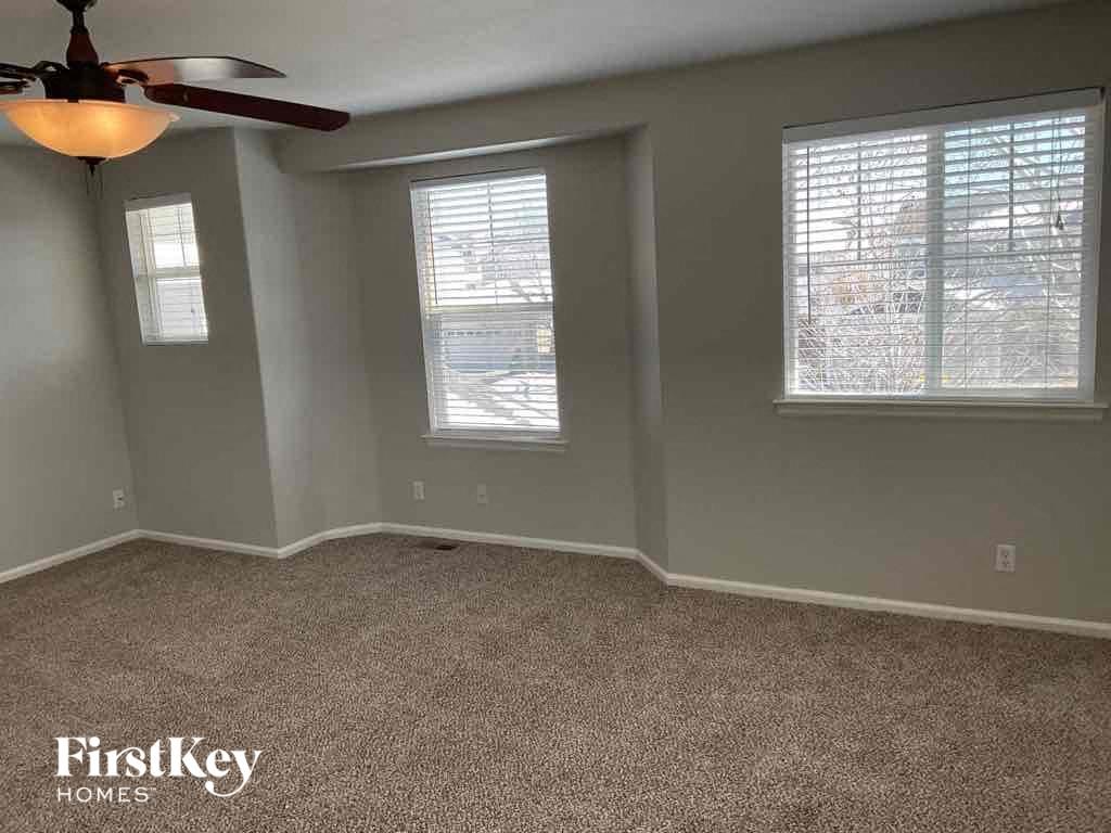 an empty living room with a ceiling fan and two windows