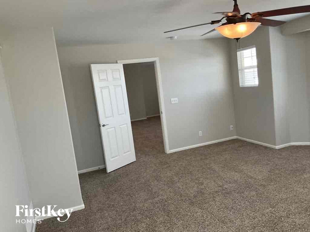 an empty living room with a ceiling fan and a closet