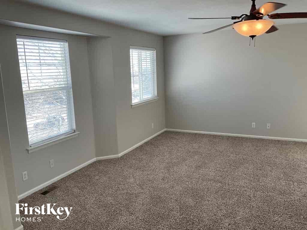 a carpeted room with a ceiling fan and two windows