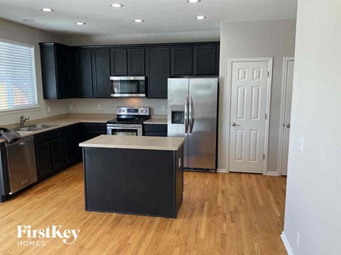 a kitchen with black cabinets and a stainless steel refrigerator