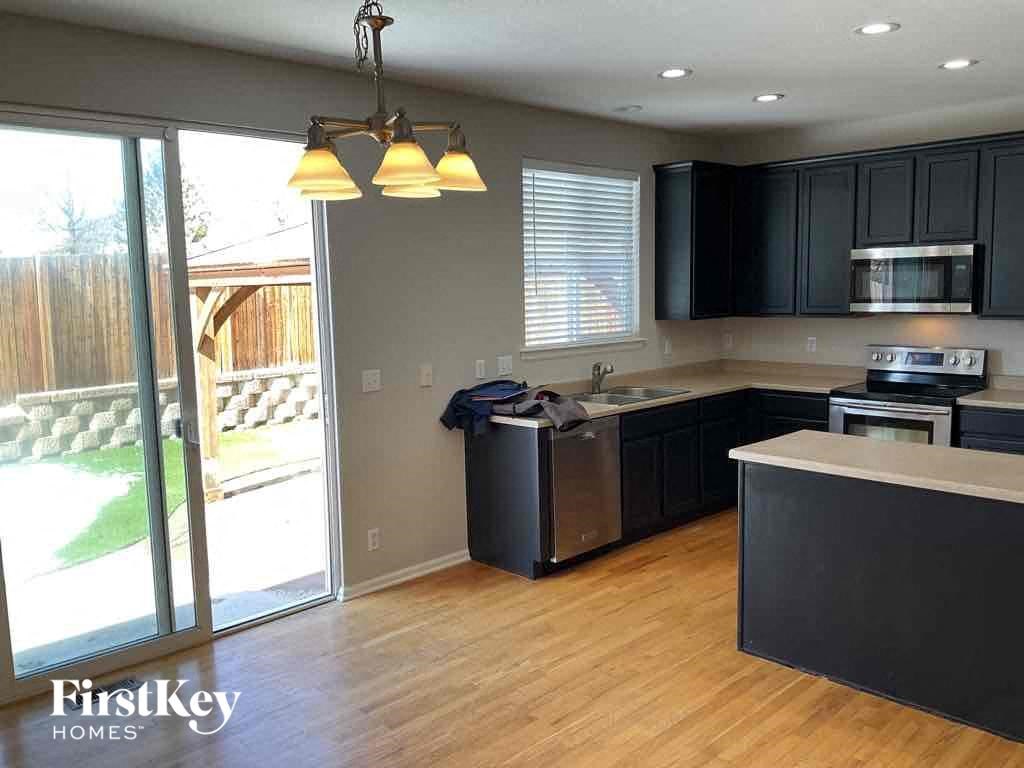an empty kitchen with black cabinets and a sliding glass door