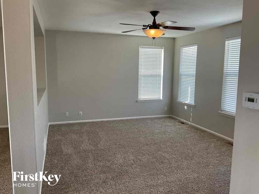 an empty living room with a ceiling fan