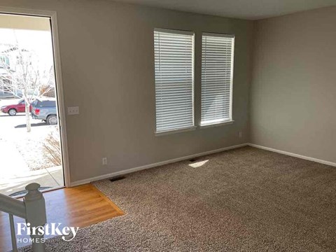 an empty living room with a wooden floor and two windows