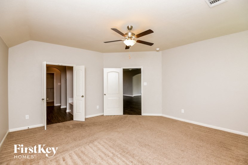 an empty living room with a ceiling fan and a carpet