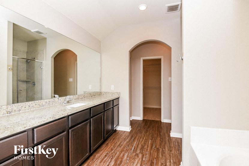 a bathroom with a sink and a mirror and a hallway