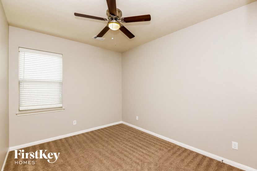 an empty room with a ceiling fan and a window