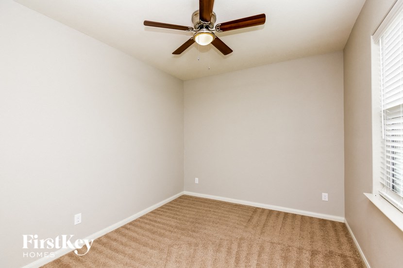 a living room with a ceiling fan and a carpet