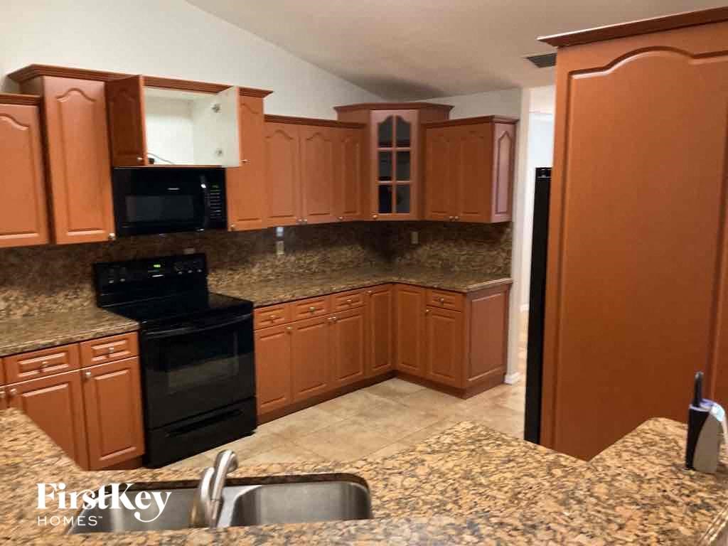an empty kitchen with brown cabinets and black appliances