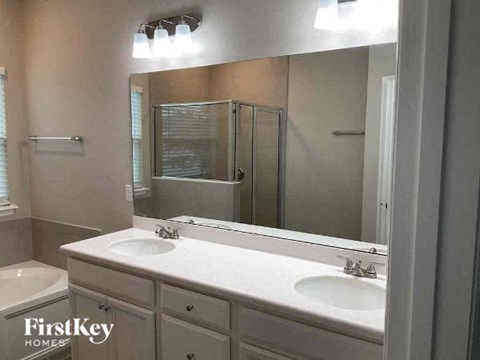 A bathroom with a white countertop and a mirror above it.