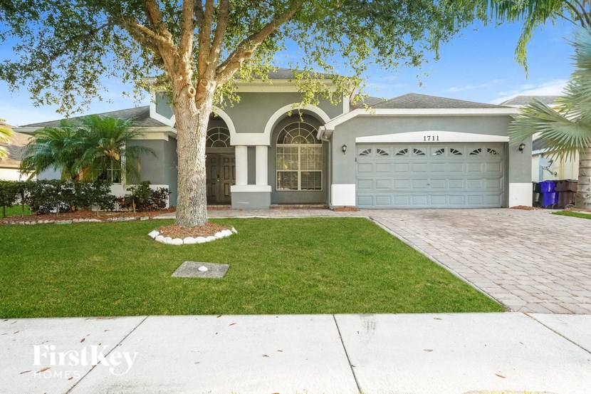 a house with a driveway and a tree in front of it