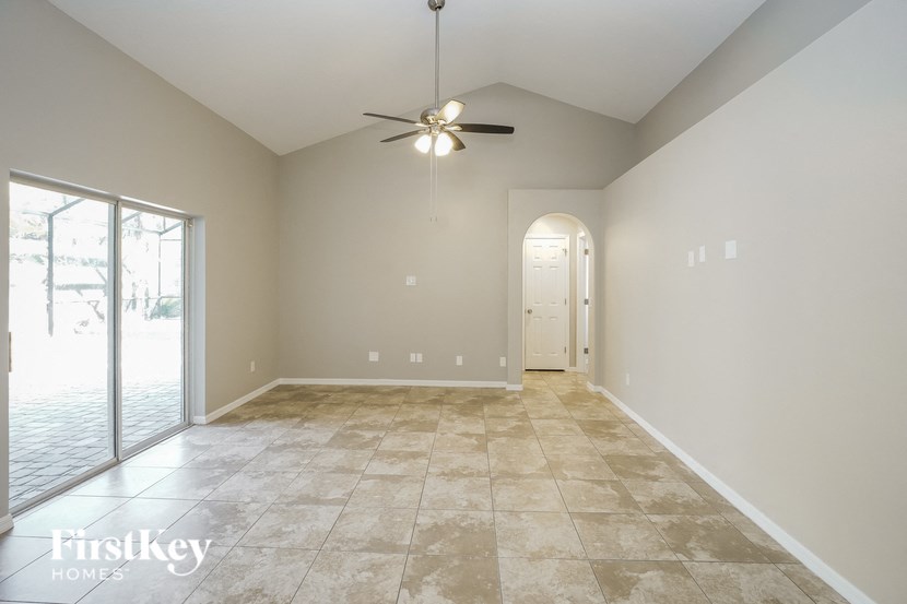 a empty living room with a ceiling fan and a glass door