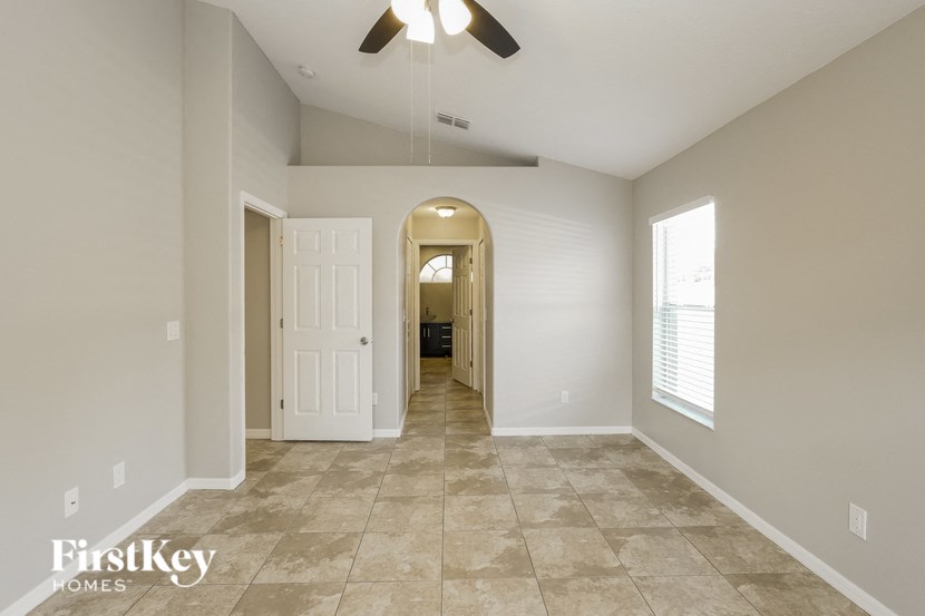an empty hallway with a ceiling fan and a door to a room
