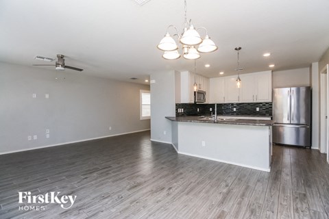 A spacious kitchen and living room with wood flooring and a ceiling fan.