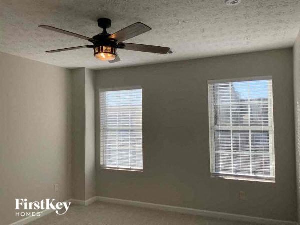 a bedroom with a ceiling fan and two windows