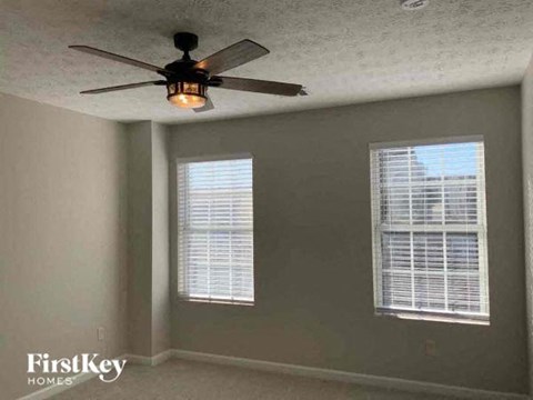 a bedroom with a ceiling fan and two windows