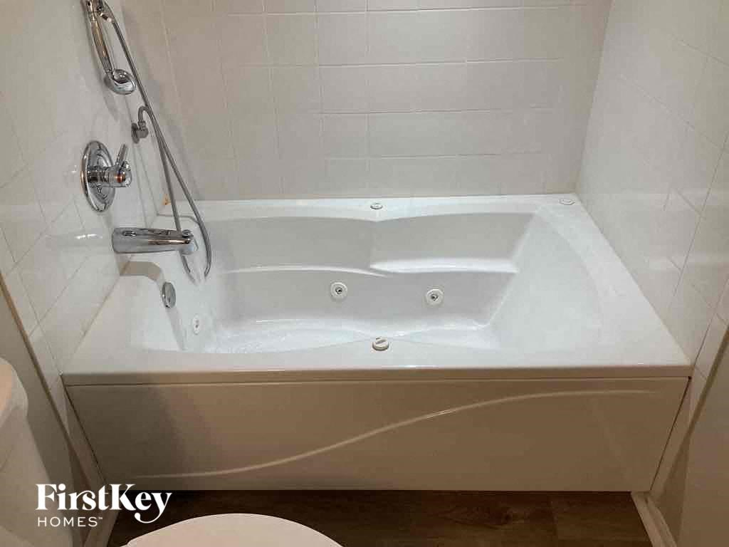 a white bath tub with a shower in a bathroom