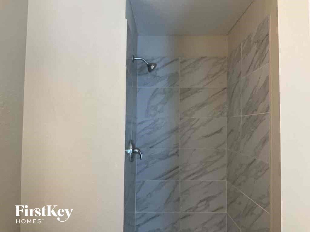 a walk in shower in a bathroom with a marble shower door