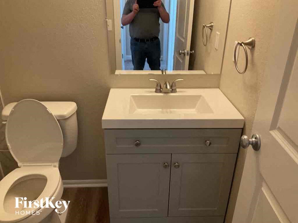 a man taking a picture of a bathroom with a sink and toilet