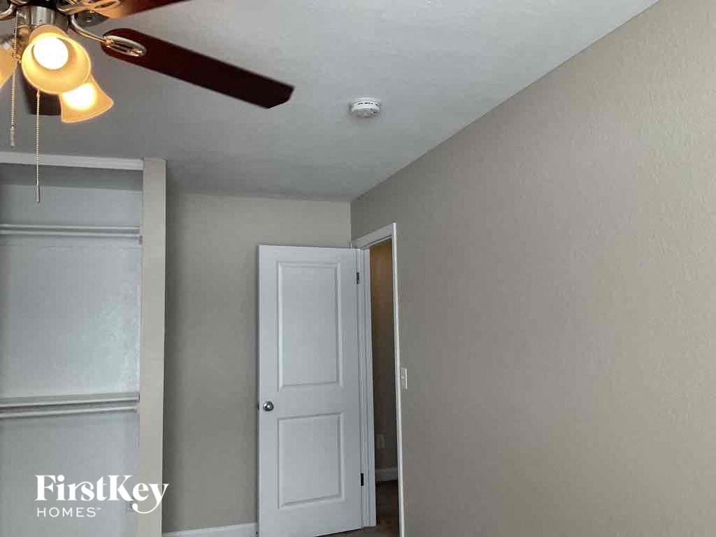 a bedroom with a ceiling fan and a door to a closet