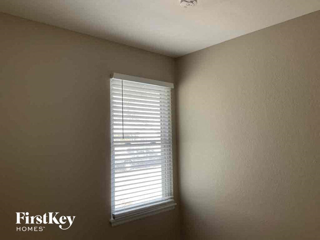 a window with white blinds in a room with a white wall